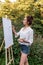 woman paints picture landscape, girl artist, summer forest, creating creativity artistic mood. Blank white canvas