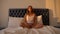 Woman in pajamas meditating in lotus pose sitting on bed, morning relaxation