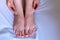 Woman palpates hand leg ankle hygroma in joint, feet closeup view.