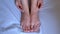 Woman palpates hand leg ankle hygroma in joint, feet closeup view.