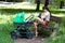 Woman parent is sitting on wooden bench in the park, holding and breastfeeding baby, next to stroller, sunny day in public park