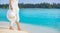 woman with pareo and hat relaxes walking on the white sand of a beach in the Maldives