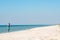 Woman in a pareo walks along the sandy deserted beach