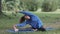 a woman in the park is stretching on a blue yoga mat. jogging and warming up in a public place, a European millennial