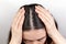 The woman parted her dark hair with her hands, showing dandruff. Close up. The view from the top. White background. The concept of