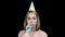 Woman in party hat happy birthday blowing party horn on black background