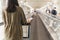 Woman passenger holding boarding pass ticket walking on escalator with trolley.