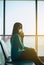 Woman passenger holding mobile phone and checking flight or online check in and travel planner at international airport