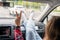 Woman passenger, legs in a jeans and socks on car dashboard while travel on the highway.  Girl showing victory sign hand. Freedom.