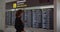 Woman passenger looking at timetable board screen at the airport, international flight