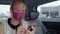 Woman passenger in taxi wearing mask and using phone