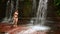 woman passing through waterfall in borneo rainforest