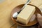 Woman pastry chef hand holding a piece of organic healthy vegetarian new York cheesecake, ceramic plate and spoon on