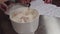 Woman pastry cook puts crumbs into mixing bowl with whipped cream