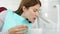 Woman patient in dental clinic. Rinsing out after teeth treatment. Dental equipment on background