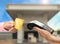 Woman paying for fuel using credit card via payment terminal at gas station, closeup