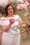 Woman peach blossom. Happy woman in white dress walking in the garden of blossoming peach trees in spring