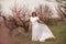 Woman peach blossom. Happy woman in white dress walking in the garden of blossoming peach trees in spring