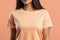 Woman in peach fuzz colored tshirt, can be used for design, mock up. The trending color of 2024.