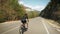 Woman pedaling bike. Cyclist twists pedals on bicycle through mountain road. Sport concept. Professional road cyclist training on