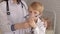 A woman pediatrician puts on an inhaler mask to a young boy in the hospital.