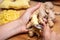 Woman is peeling ginger with a teaspoon, chopped bites in the back