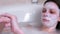 Woman peeling hands, puts a scrub on her hands lying in the foam bathroom.