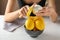 Woman peeling ripe lemons at white wooden table, closeup