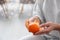 Woman peeling tangerine on blurred background, closeup. Space for text