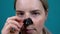 Woman peels off a black mask on her nose against black dots on the skin