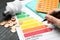 Woman with pen, energy efficiency rating chart, coins, light bulb and calculator at table