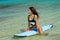 Woman with perfect body sitting on surfboard