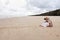 Woman and pet dog sitting on beautiful deserted beach