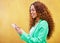 Woman, phone and typing on yellow background for communication, social media and tech chat. Happy female model