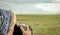 A woman photographer photographing sleeping lions on the plains of Africa from a safari jeep.