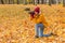 Woman photographer takes an object on a camera against a background of fallen autumn leaves