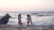 A woman photographer takes a reportage photo of two cute babies playing on the beach by the sea at sunset