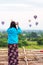 Woman photographing balloons in Bagan, Myanmar. Copy space for text. Back view. Vertical.