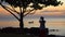 The woman photographs a decline with the boat on the smartphone. Boat on open sea sunset horizon.