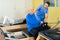 Woman physiatrist helping aged man doing exercises on reformer
