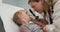 Woman physician using ophthalmoscope to look into eyes of a little boy