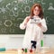 A woman physics teacher stands at the blackboard with weights in her hand. Physics lesson in a school class