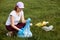 Woman picking up plastic bottles and rubbish from meadow, environmental activist collecting plastic garbage, volunteer picking up