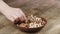 Woman Picks Up a single walnut, To Eat, From Her Bowl. took a nut on the left side