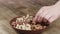 Woman Picks Up a single walnut, To Eat, From Her Bowl. took a nut on the left side