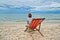 Woman picnicking and overlooking the sea sitting on a red chair at the beach