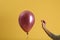 Woman piercing balloon with needle on color background