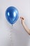 Woman piercing balloon with needle on white background