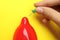 Woman piercing inflated condom with pin on background, closeup. Safe sex