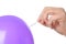 Woman piercing purple balloon on white background